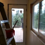 Shipping container home interior framing with view to wooden deck and forest surroundings at Highland & Co. Acres
